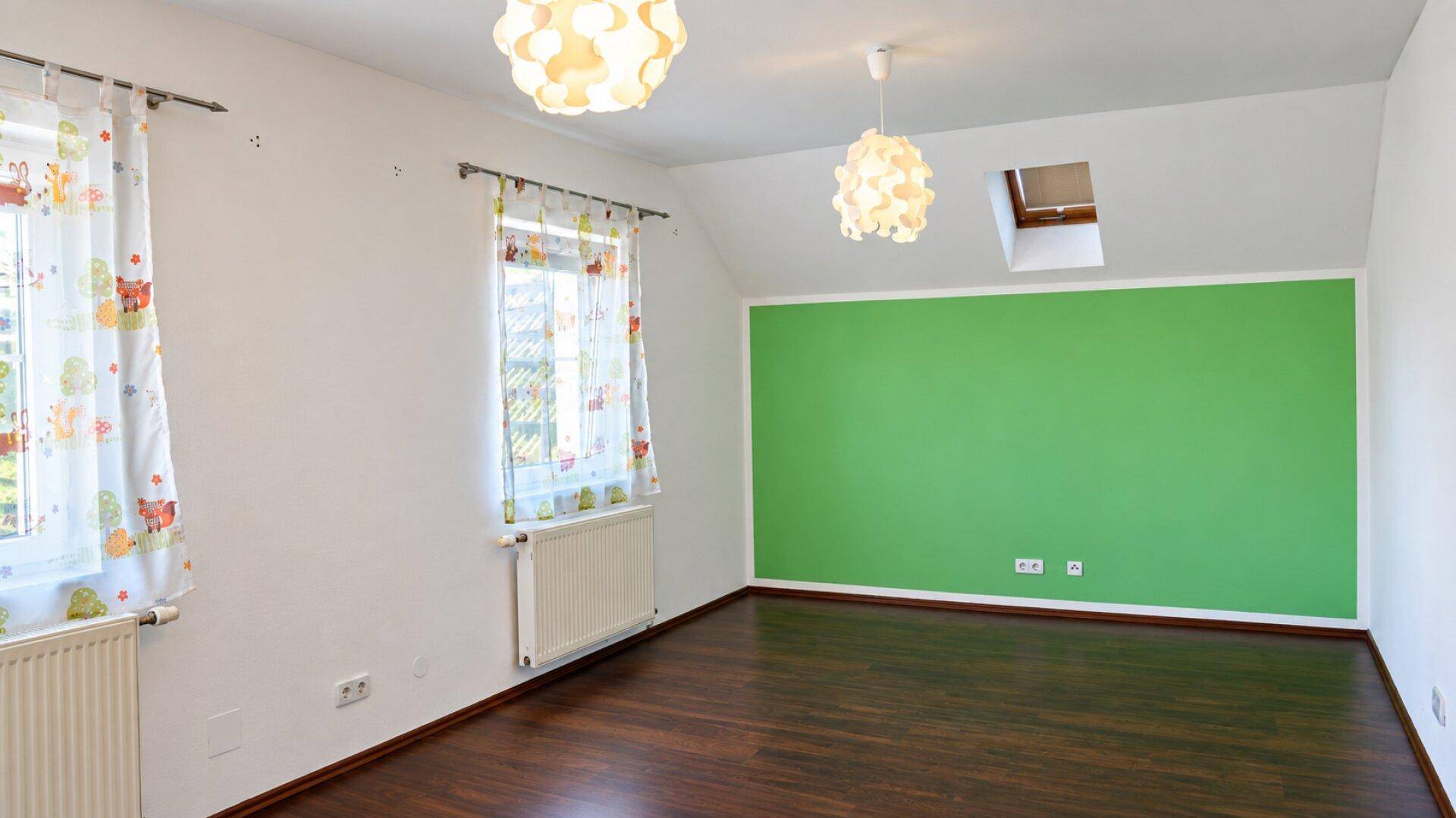 Helles Kinderzimmer mit grüner Akzentwand, Dachschräge und Laminatboden.