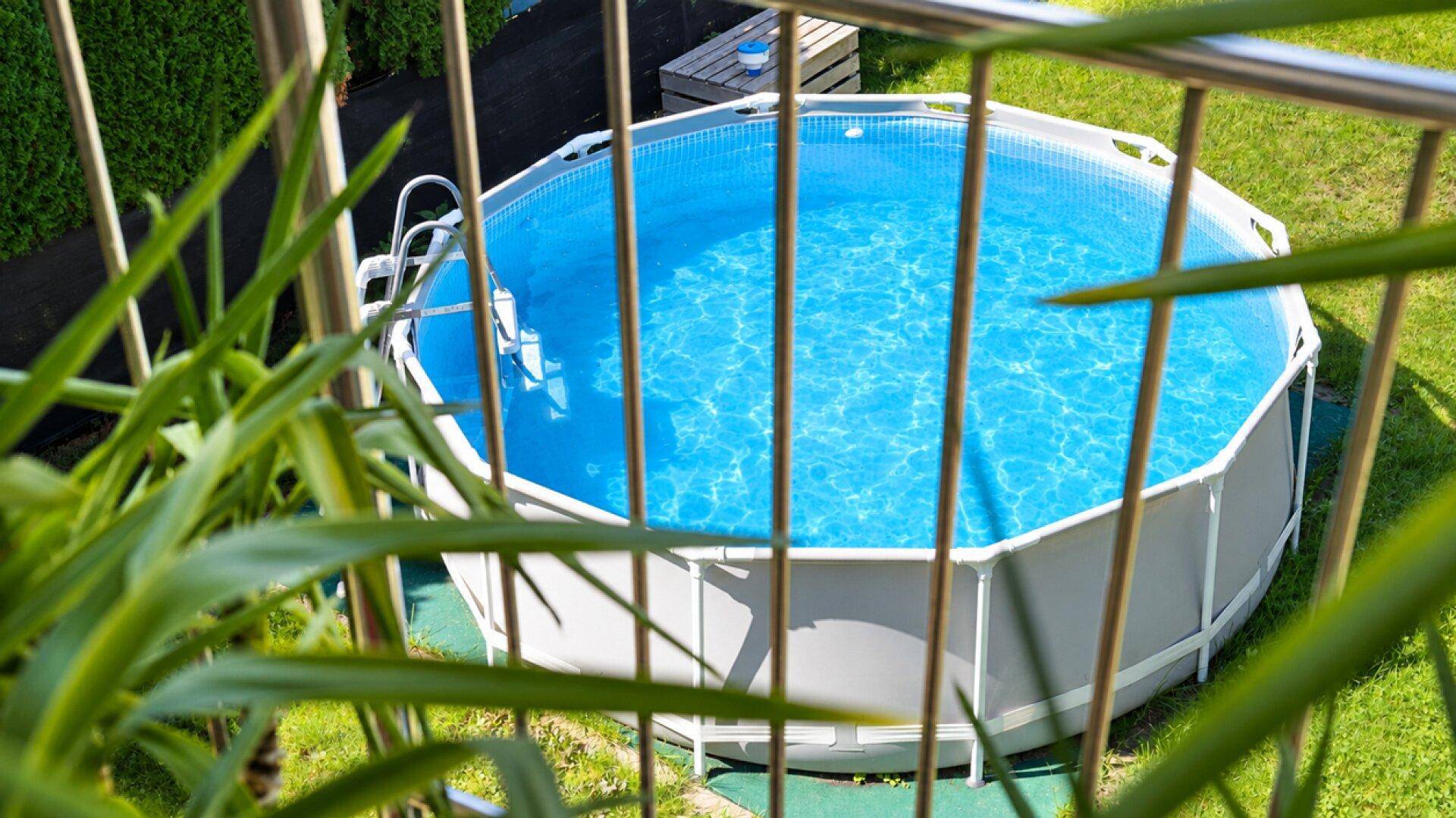 Runder Aufstellpool im Garten, umgeben von grünem Rasen und Hecken.