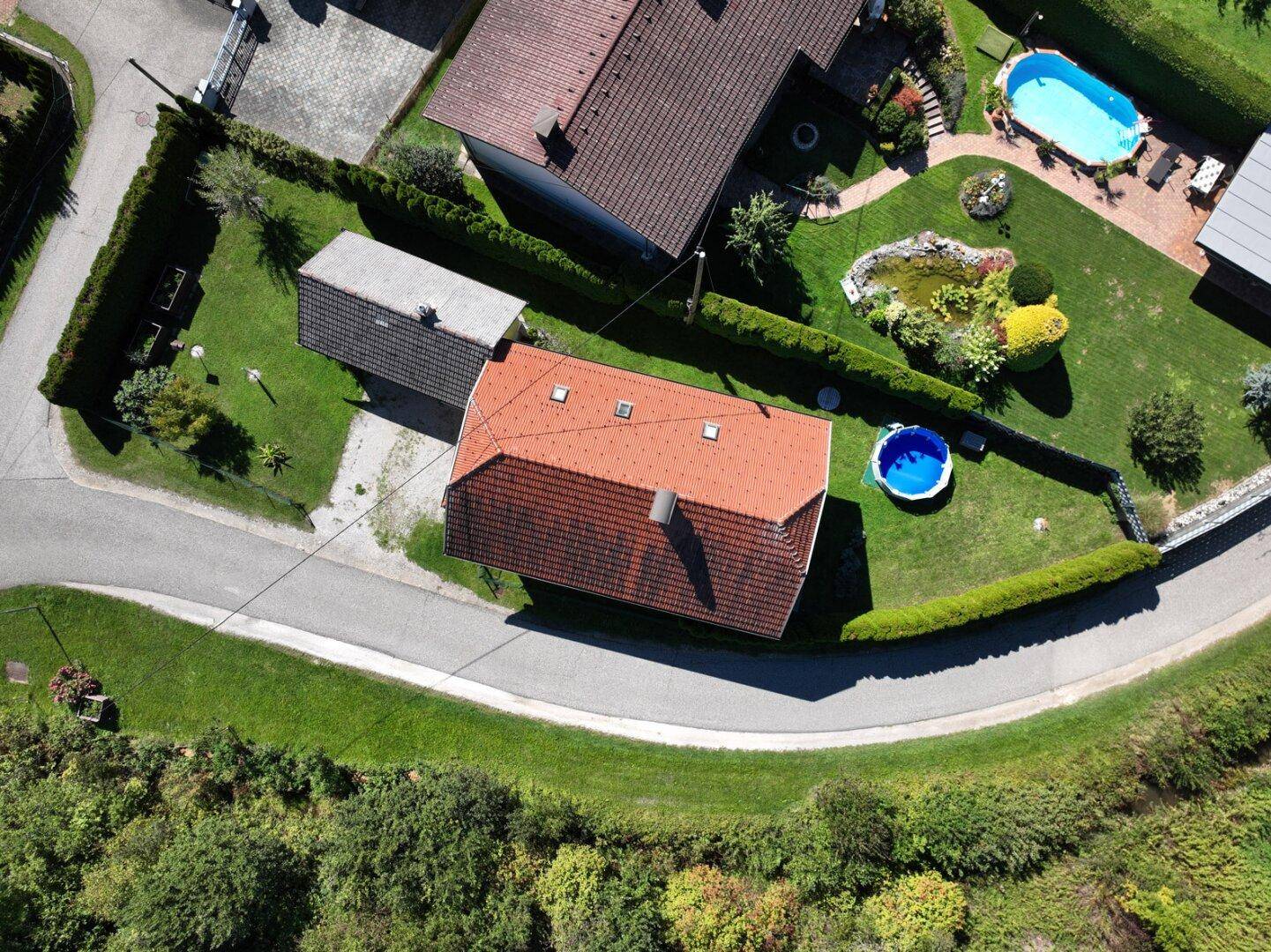 Draufsicht der Immobilie mit Garten, Aufstellpool und dem angrenzenden Nachbargrundstück mit Pool.