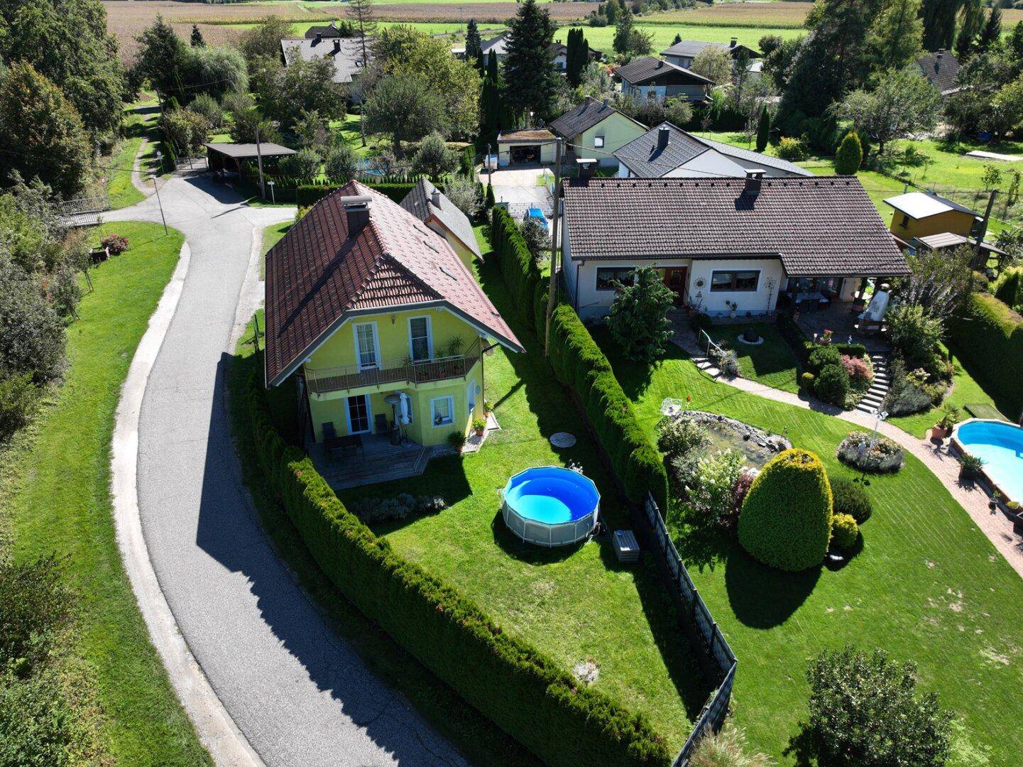Luftaufnahme des Hauses mit Garten, kleinem Aufstellpool und gepflegten Hecken.