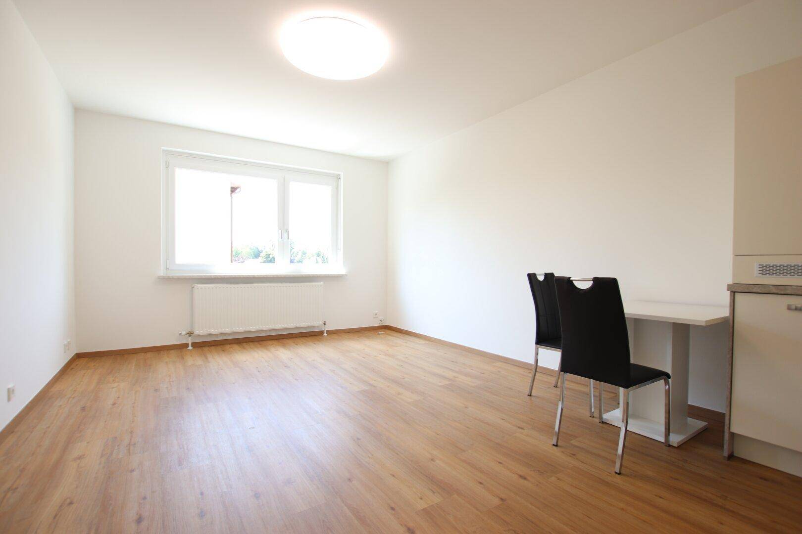Heller Raum mit großem Fenster, Heizkörper und Laminatboden, ideal als Wohn- oder Schlafzimmer.