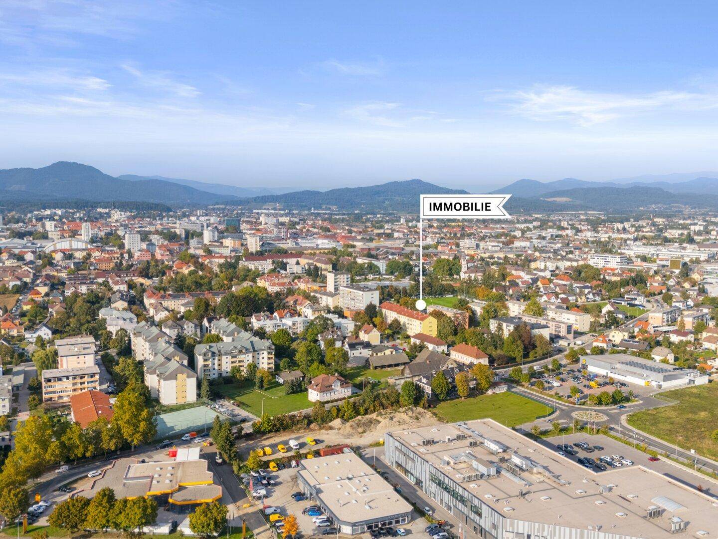 Weitläufige Luftaufnahme der Stadt mit umliegender Landschaft und markiertem Standort.