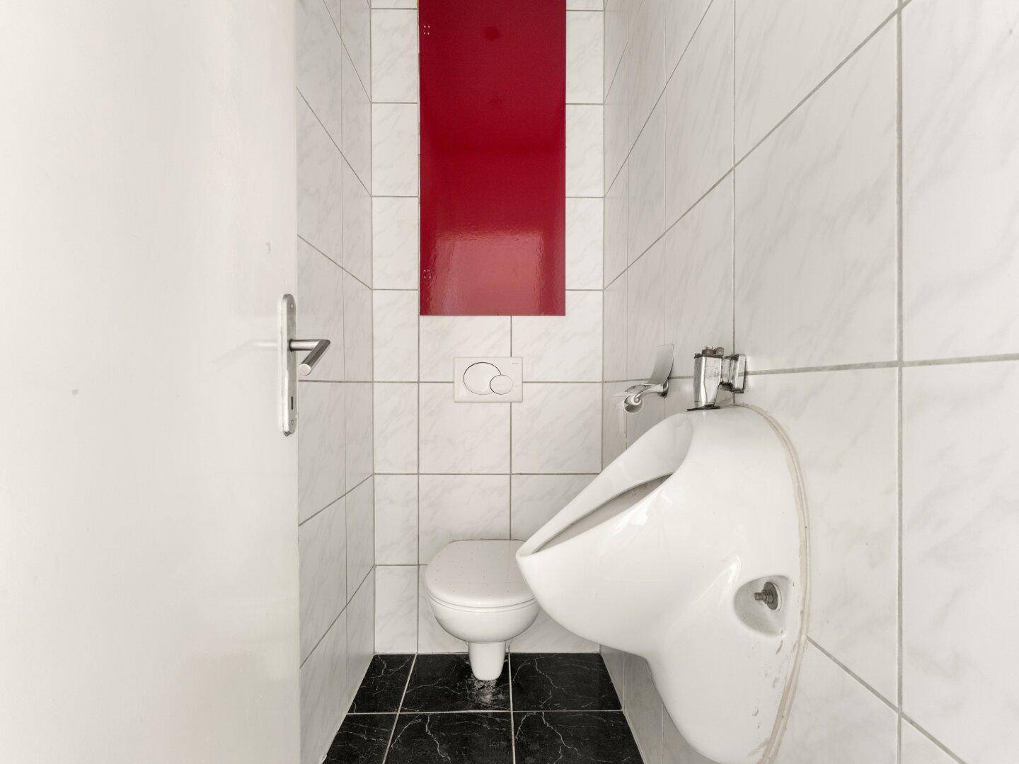 Kleines WC mit weißen Fliesen, Toilette und Urinal.