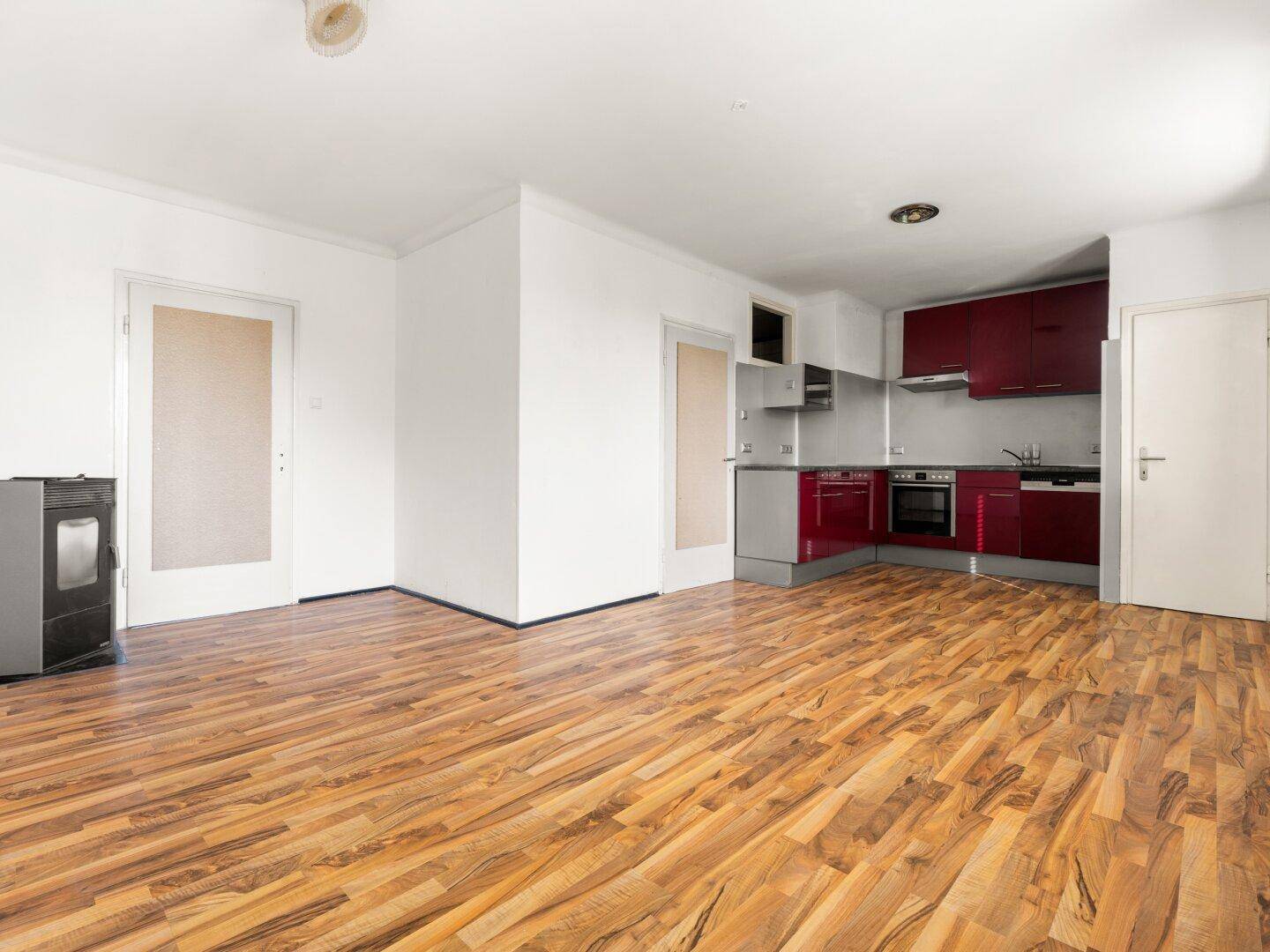 Geräumiger Wohnbereich mit offener Küche, Laminatboden und einem Holzofen.