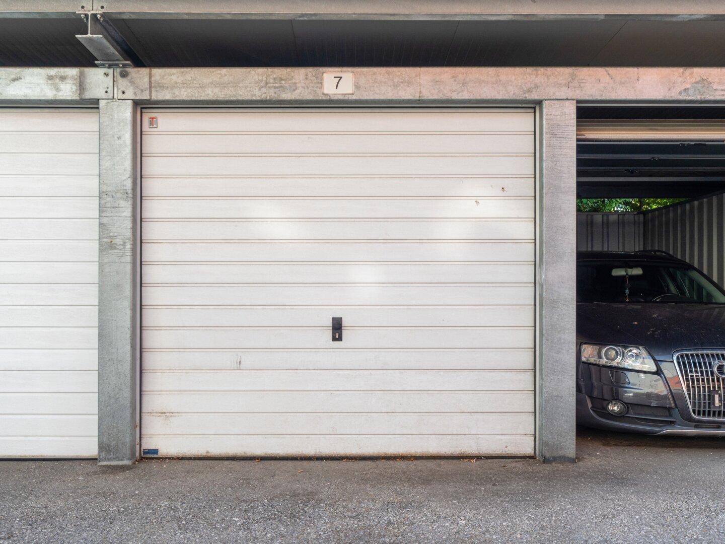 Garagentor einer Einzelgarage, die teilweise geöffnet ist und ein Auto zeigt.