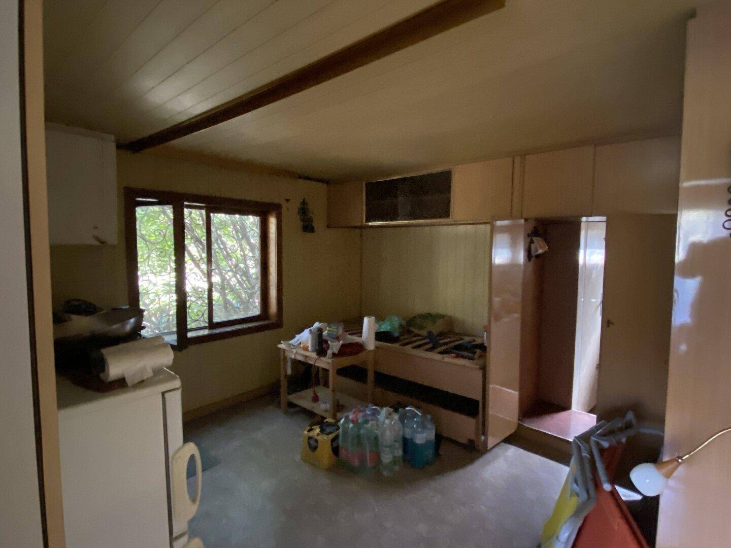 Einfache Küche mit Kühlschrank, Herd und Stauraum in einem kleinen Raum, funktional eingerichtet.