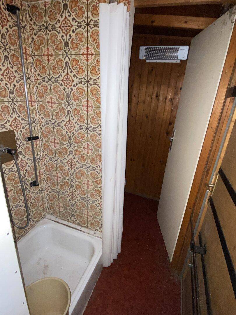 Kleines Badezimmer mit Duschwanne und gemusterten Wandfliesen, einfach und funktional.