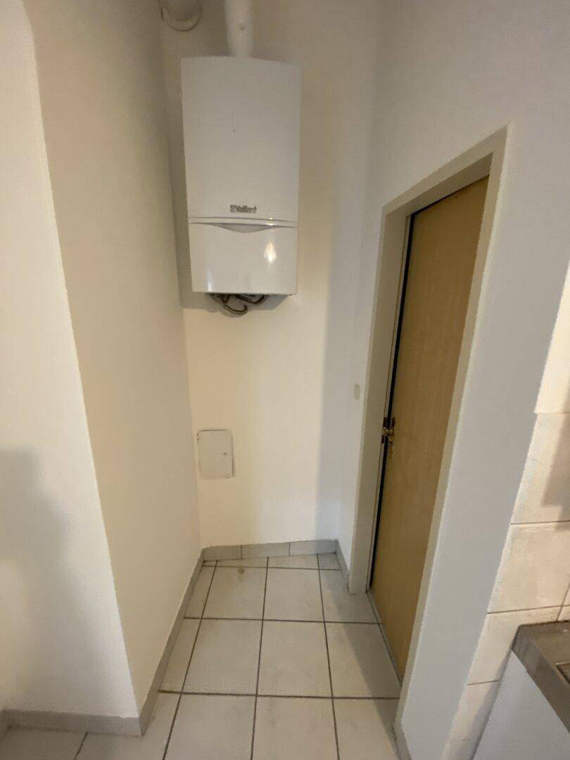 Ecke mit wandmontierter Gastherme und weißem Fliesenboden, gut gepflegt.