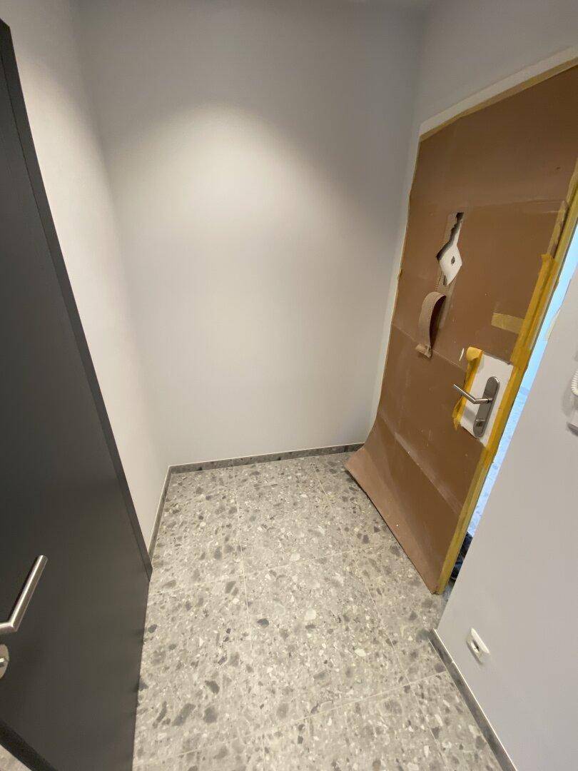Eingangsbereich mit Fliesenboden und temporärem Türschutz, der auf eine neue Immobilie hindeutet.