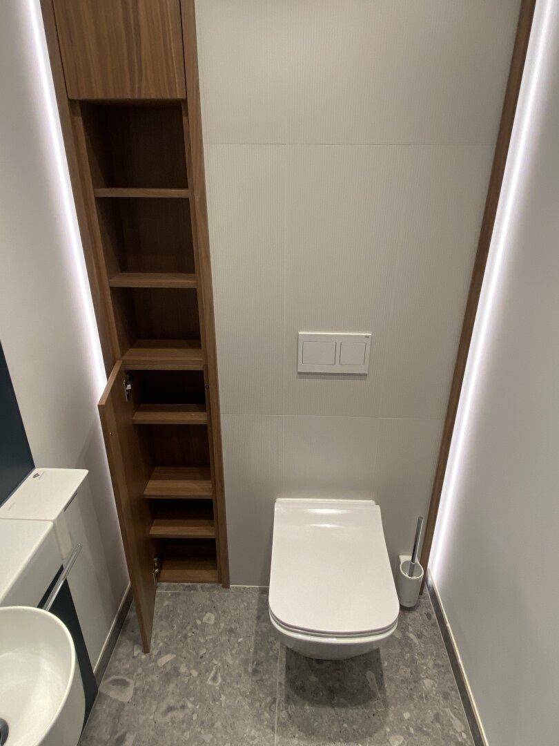 Wand-WC im modernen Gäste-WC mit integriertem Stauraum und minimalistischem Design.