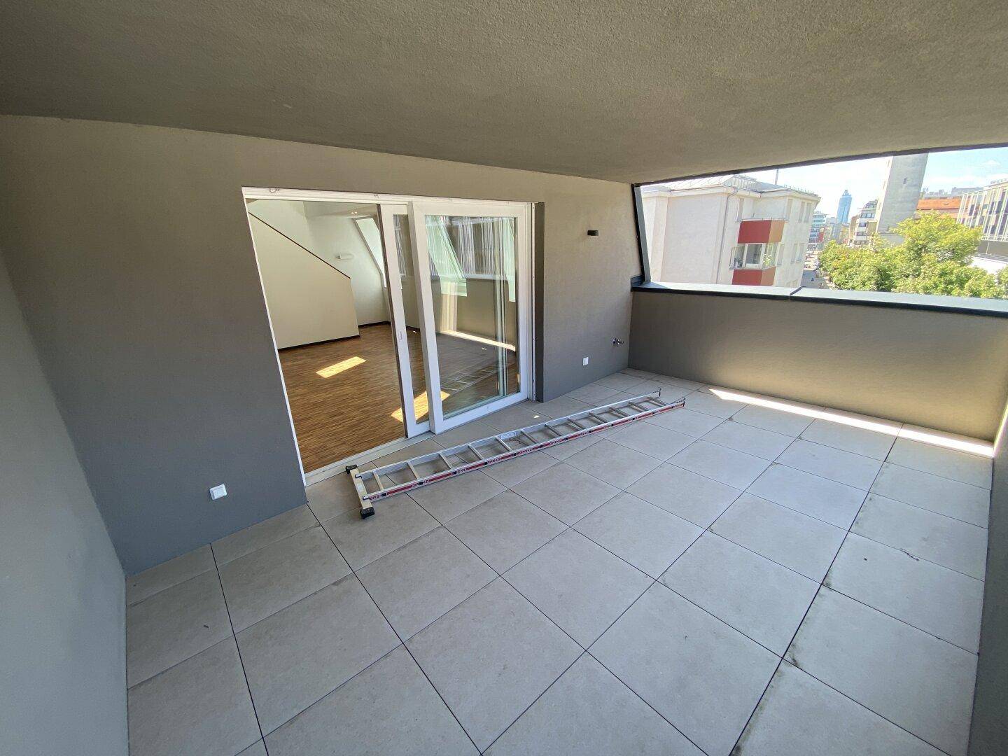 Geräumiger Balkon mit Fliesenboden und Blick auf die Stadt, zugänglich vom Wohnbereich.