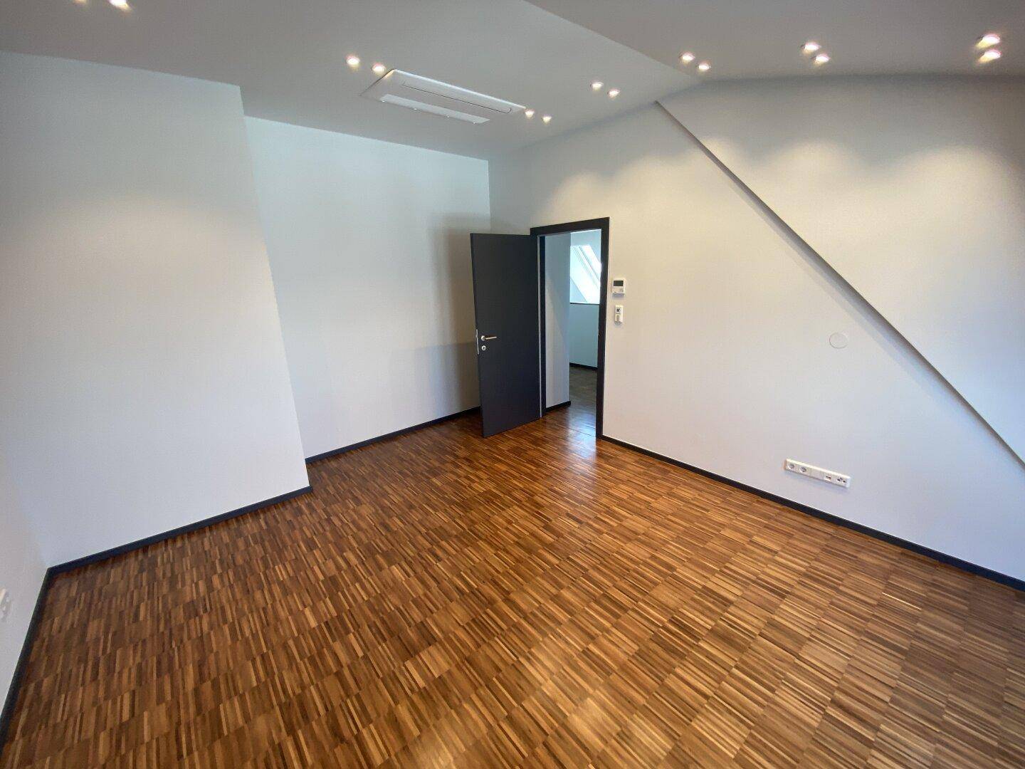 Helles Schlafzimmer mit Parkettboden, Dachschrägen und moderner Tür.