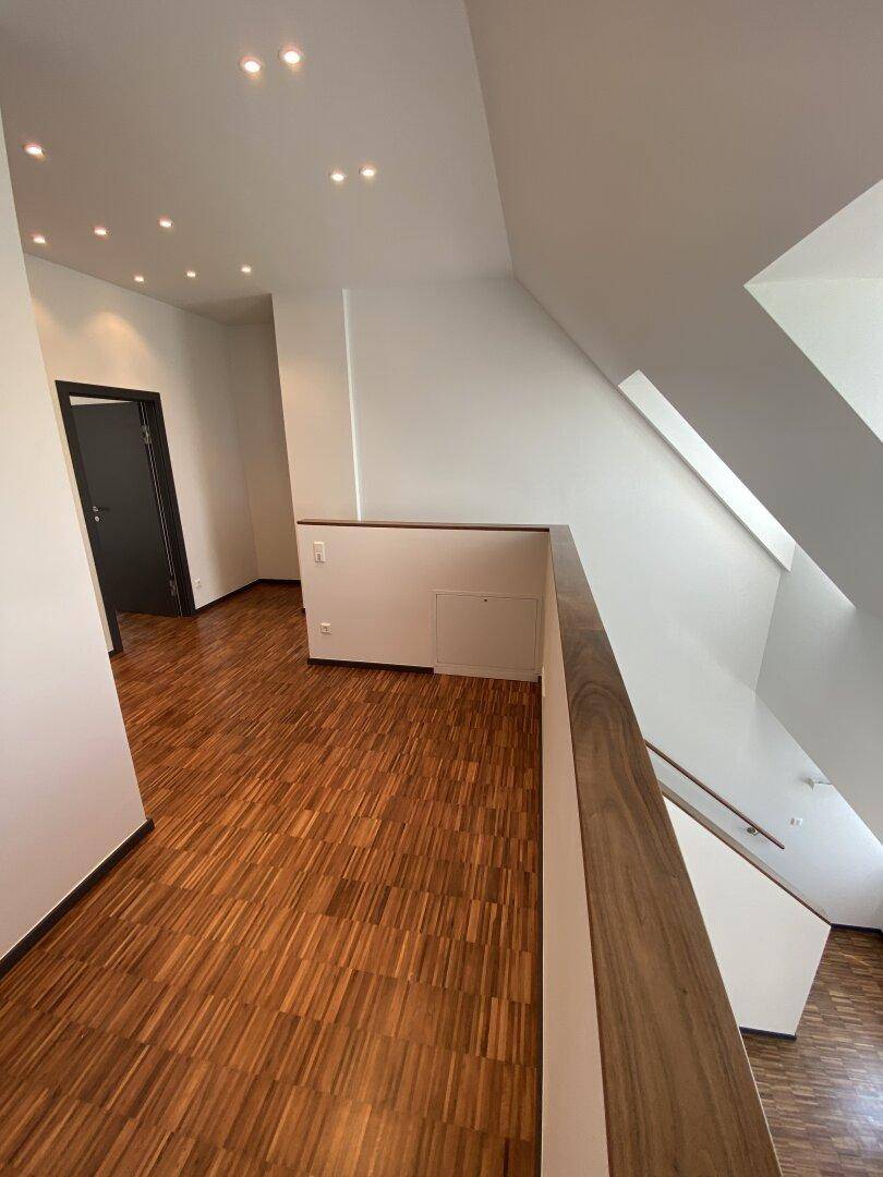 Geräumiger Flur im Obergeschoss mit Holzparkett und Einbaustrahlern, führt zu weiteren Räumen.