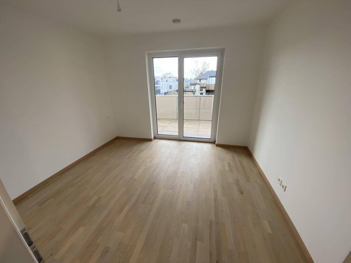 Helles Schlafzimmer mit Parkettboden und direktem Zugang zu einer sonnigen Terrasse.