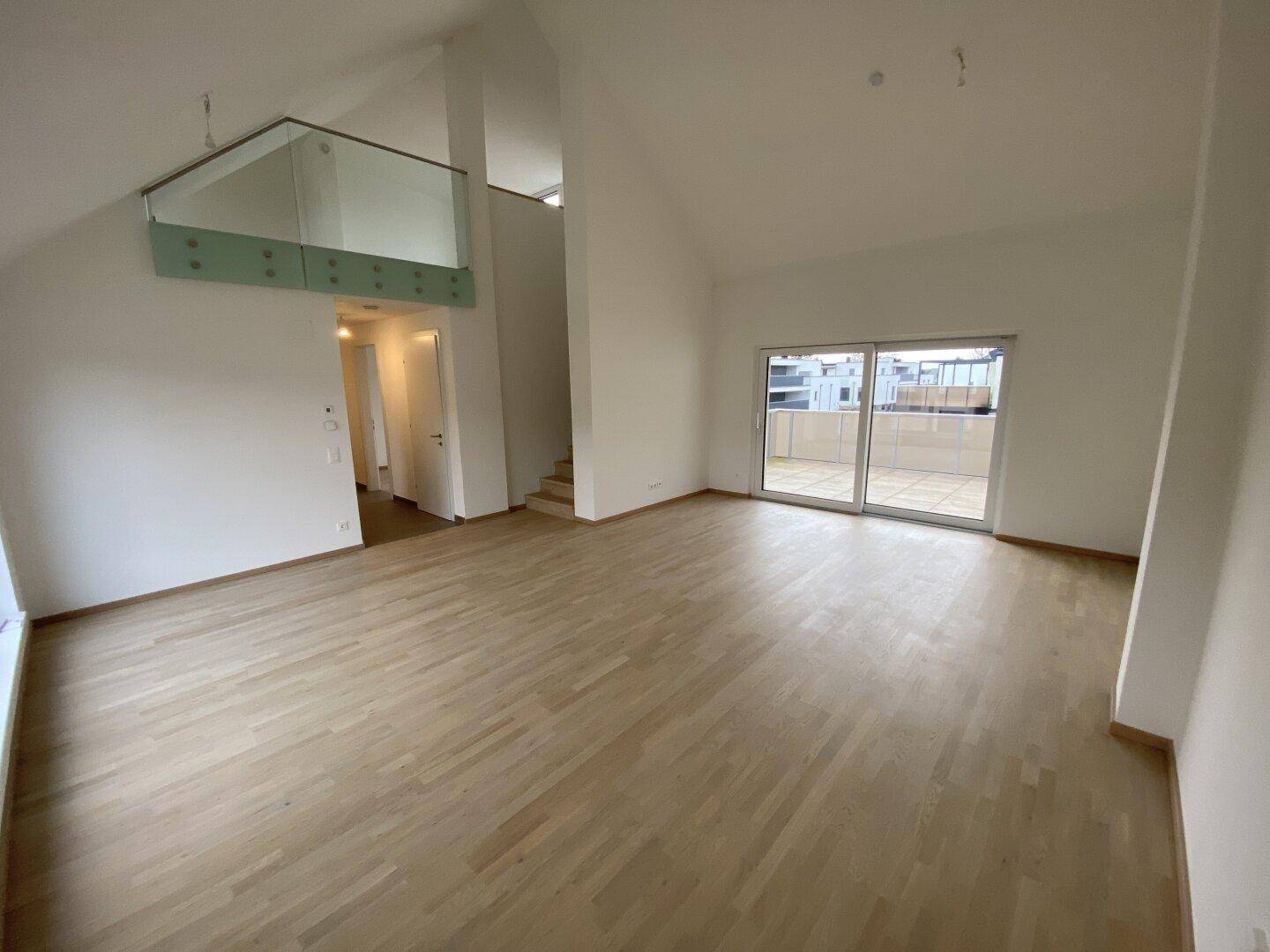 Heller Wohnbereich mit Zugang zu einer großen Terrasse und Blick auf die umliegenden Häuser.