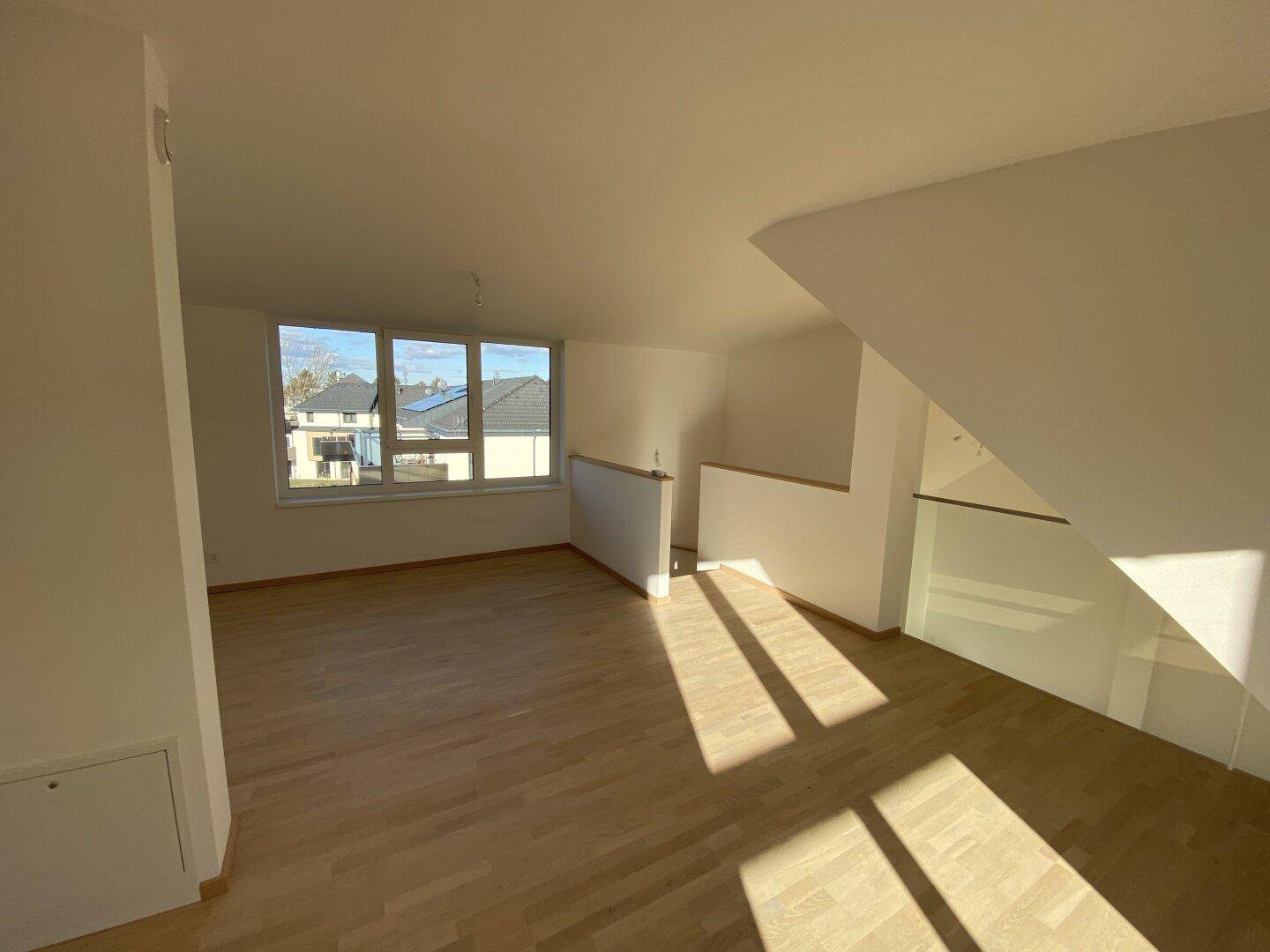 Lichtdurchfluteter Wohnbereich mit Holzboden und Blick auf die Umgebung, ideal für moderne Einrichtung.