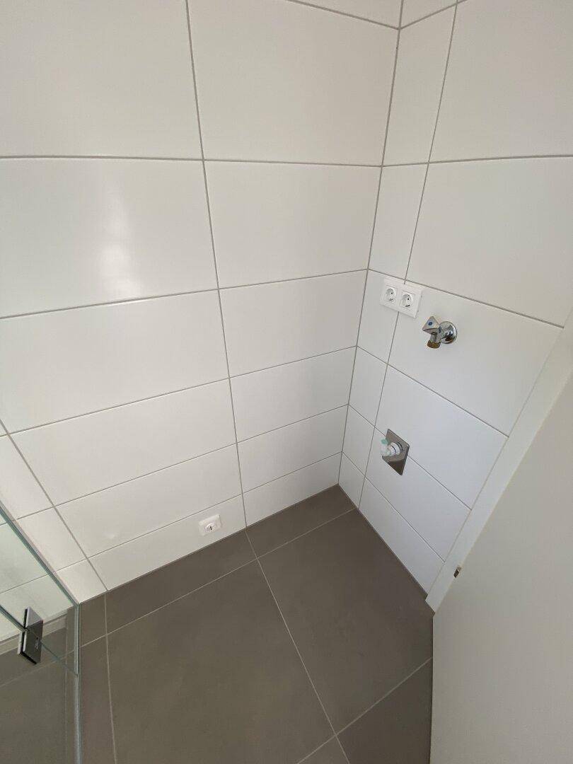 Detaillierte Ansicht des Duschbereichs mit modernen Fliesen und Anschlüssen im Badezimmer.