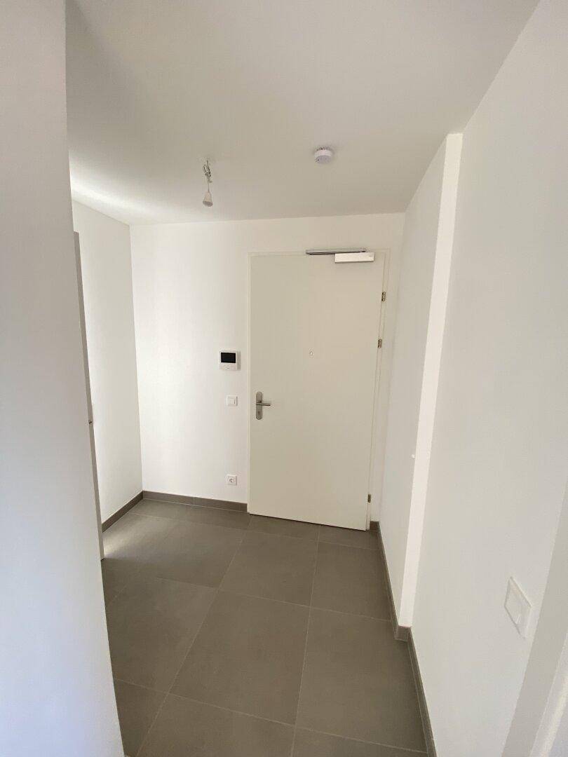 Heller Eingangsbereich mit modernen Fliesen und weißer Tür, bereit für die individuelle Gestaltung.