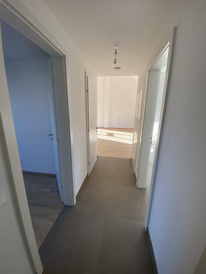 Heller Flur mit Fliesenboden, der verschiedene Räume der Wohnung miteinander verbindet.