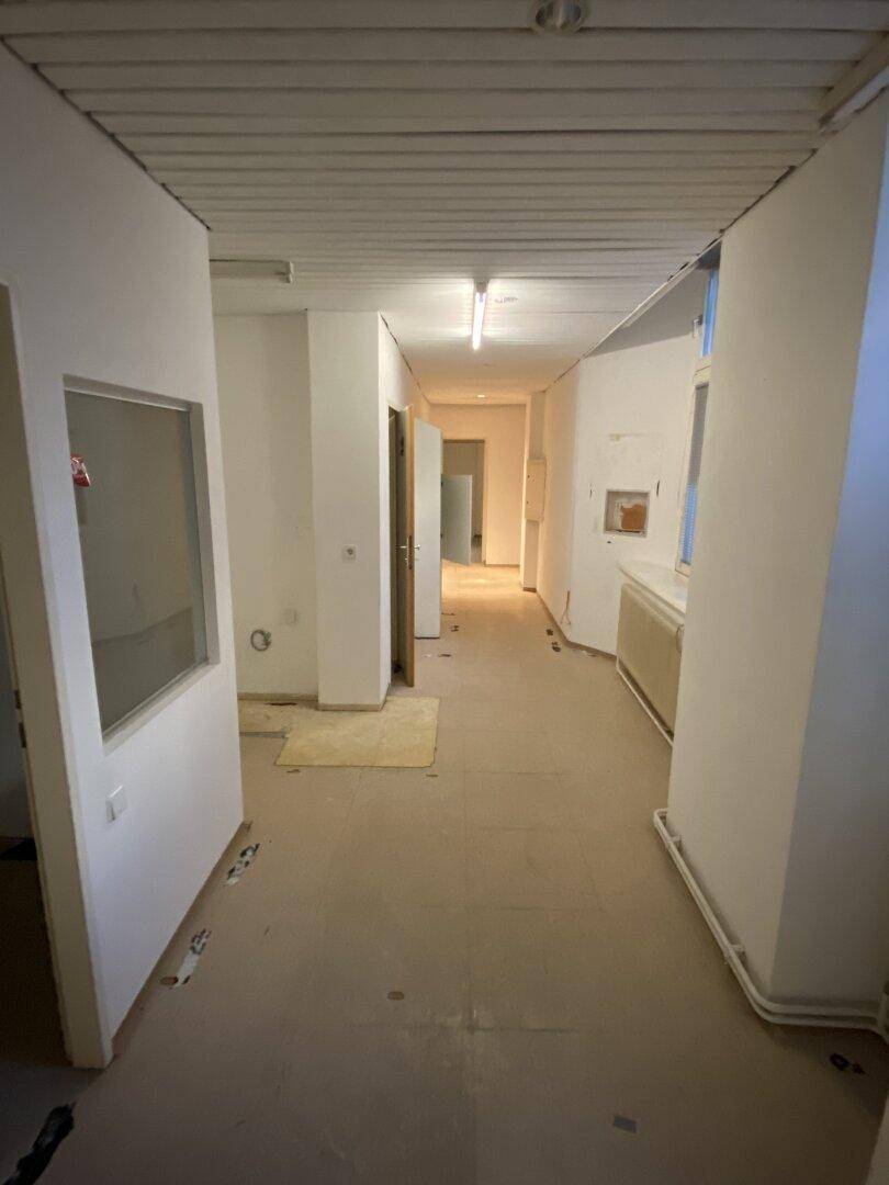 Langer Flur mit abgehängter Decke und mehreren Türen, der zu weiteren Räumen führt und auf Ausbau wartet.