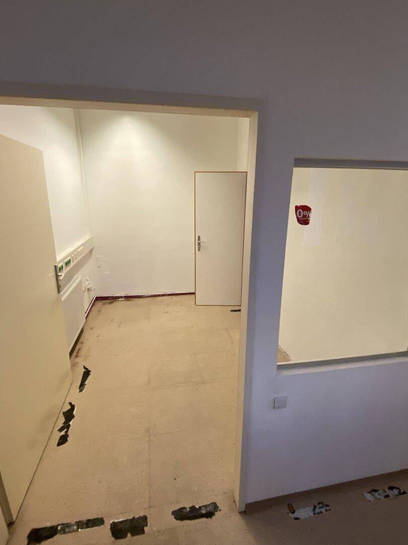 Kleiner, heller Raum mit weißen Wänden und Blick in einen weiteren Bereich, bereit für die Nutzung.