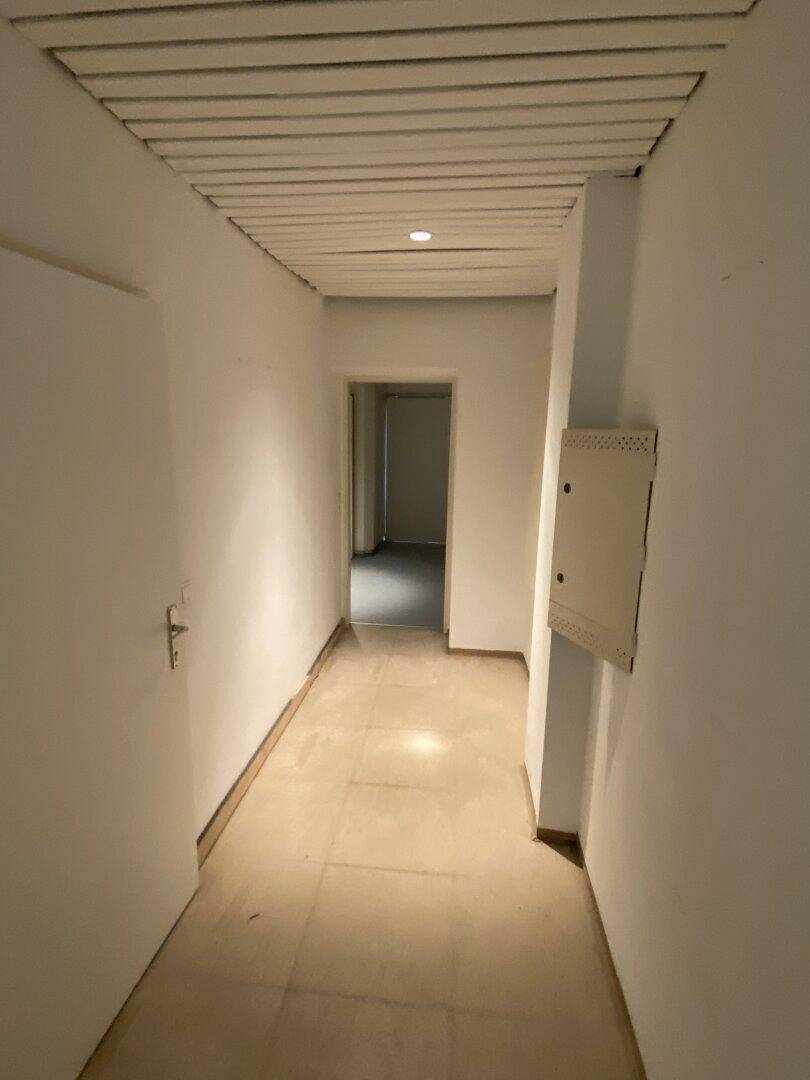 Heller Flur mit weißer Deckenverkleidung und Türen, der zu verschiedenen Räumen führt und auf Fertigstellung wartet.