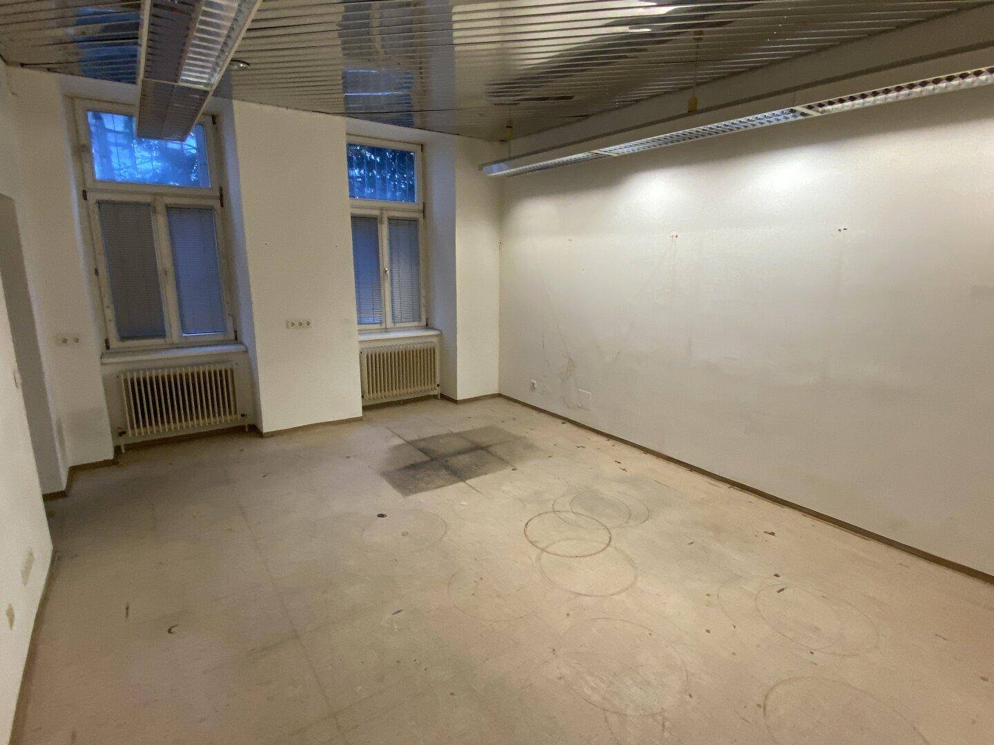 Heller Büroraum mit großen Fenstern und Heizkörpern, bereit für die Einrichtung und neue Mieter.