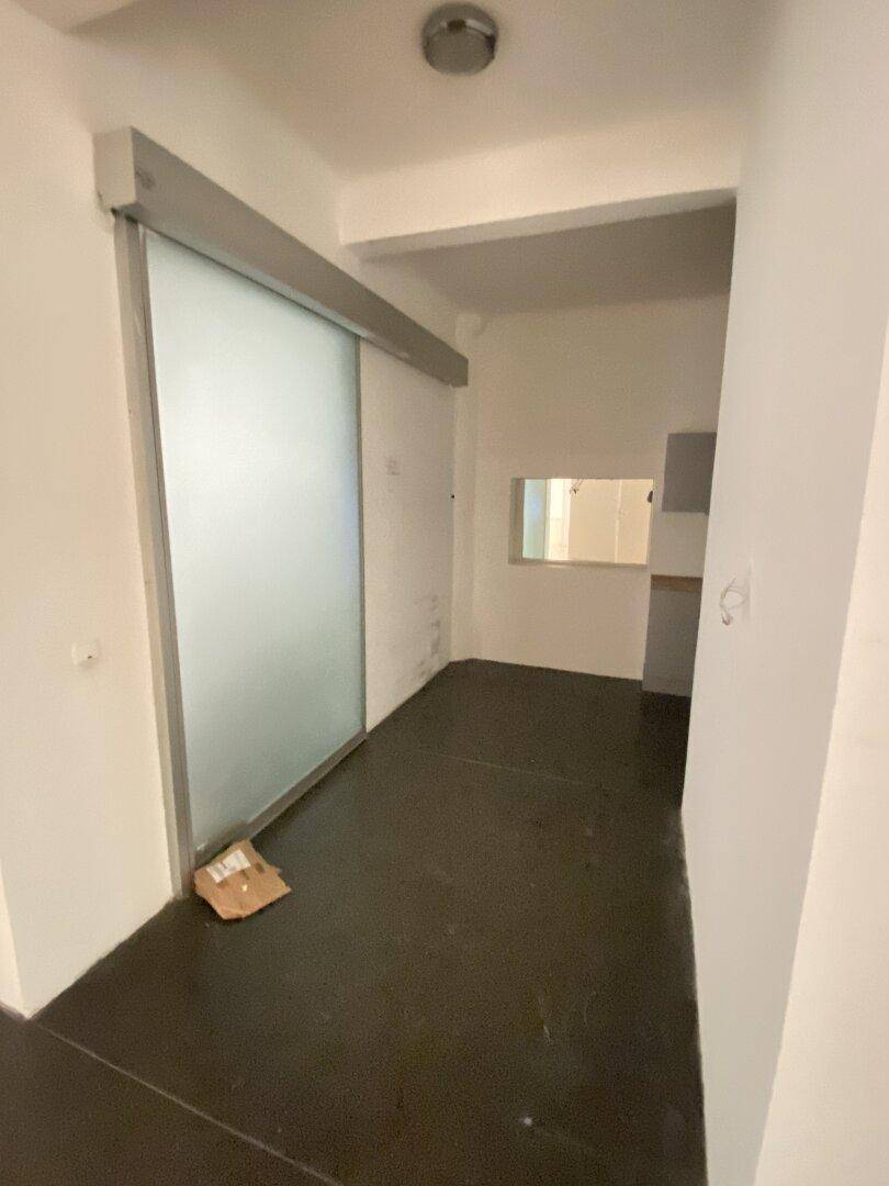 Flur mit dunklem Boden und einer modernen Schiebetür aus satiniertem Glas, führt zu weiteren Räumen.