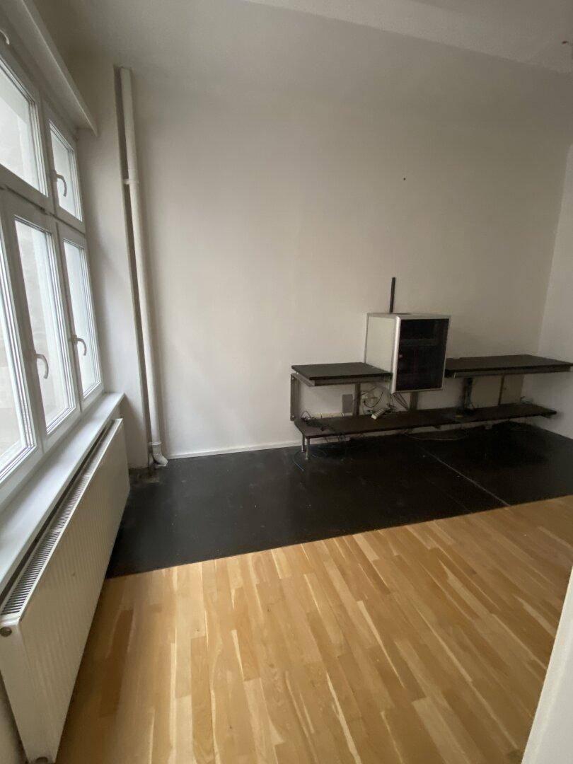 Raum mit gemischtem Bodenbelag aus Holz und dunklem Vinyl, ausgestattet mit einem Wandregalsystem.