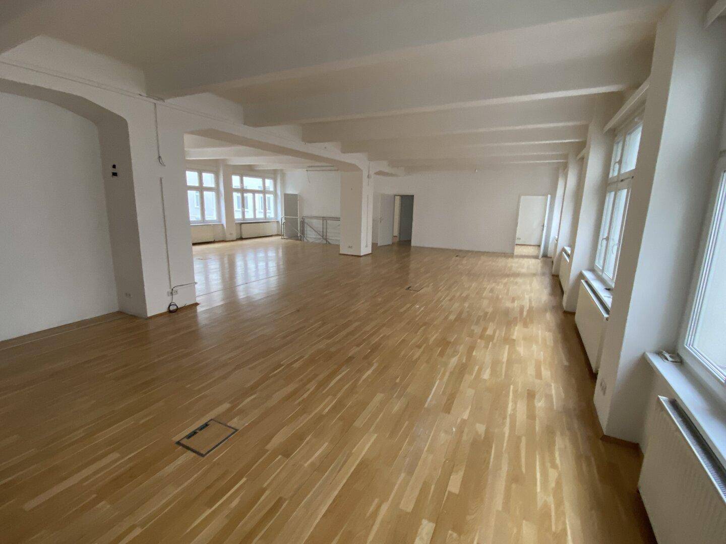 Geräumiger, heller Bürobereich mit Holzboden und hohen Decken, bietet vielseitige Gestaltungsmöglichkeiten.