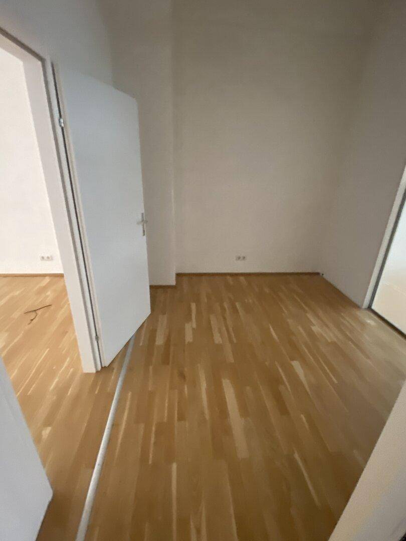 Heller, leerer Raum mit Holzparkett und weiß gestrichenen Wänden, bereit zur individuellen Gestaltung.