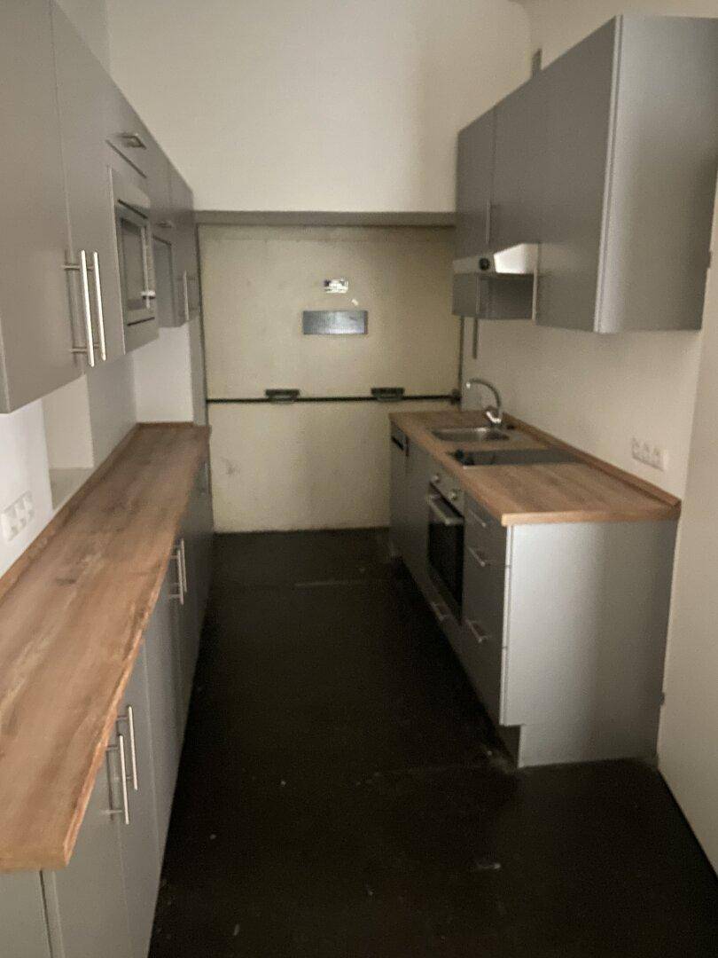 Funktionale Küchenzeile mit Spüle, Kochfeld und grauen Schränken, ideal für kleine Büros oder Apartments.