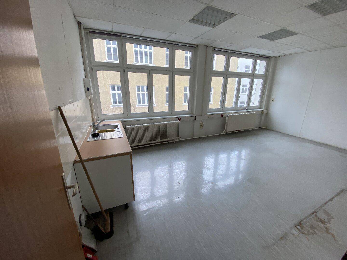 Heller Raum mit Fenstern und einer einfachen Küchenzeile, ideal als Pausenraum oder kleine Teeküche.