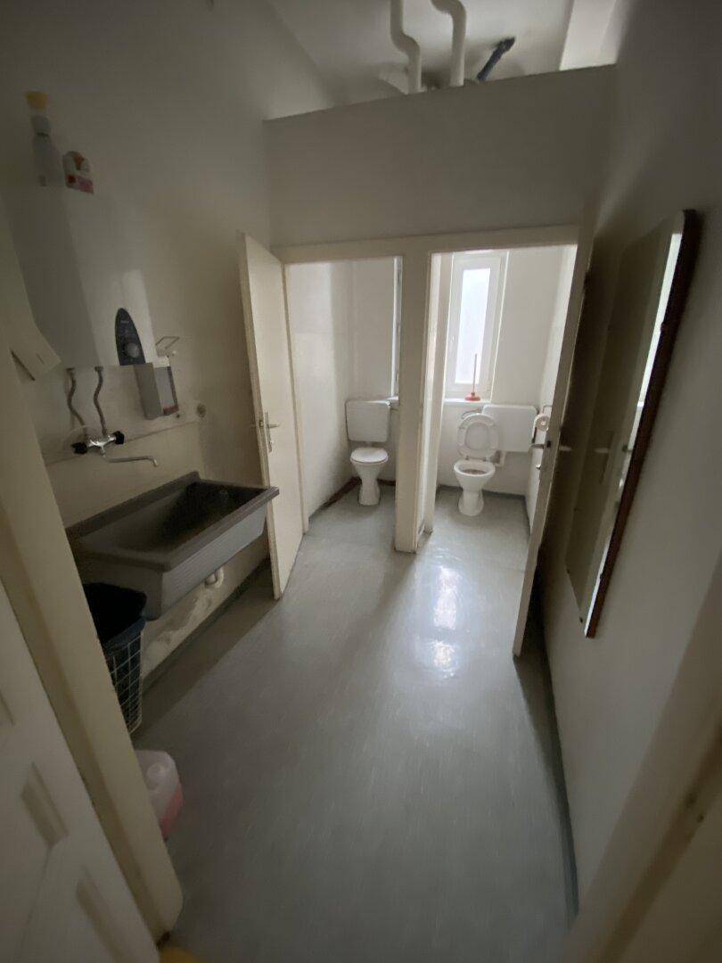 Sanitärbereich mit mehreren Toilettenkabinen und einem Waschbecken, funktional und sauber.