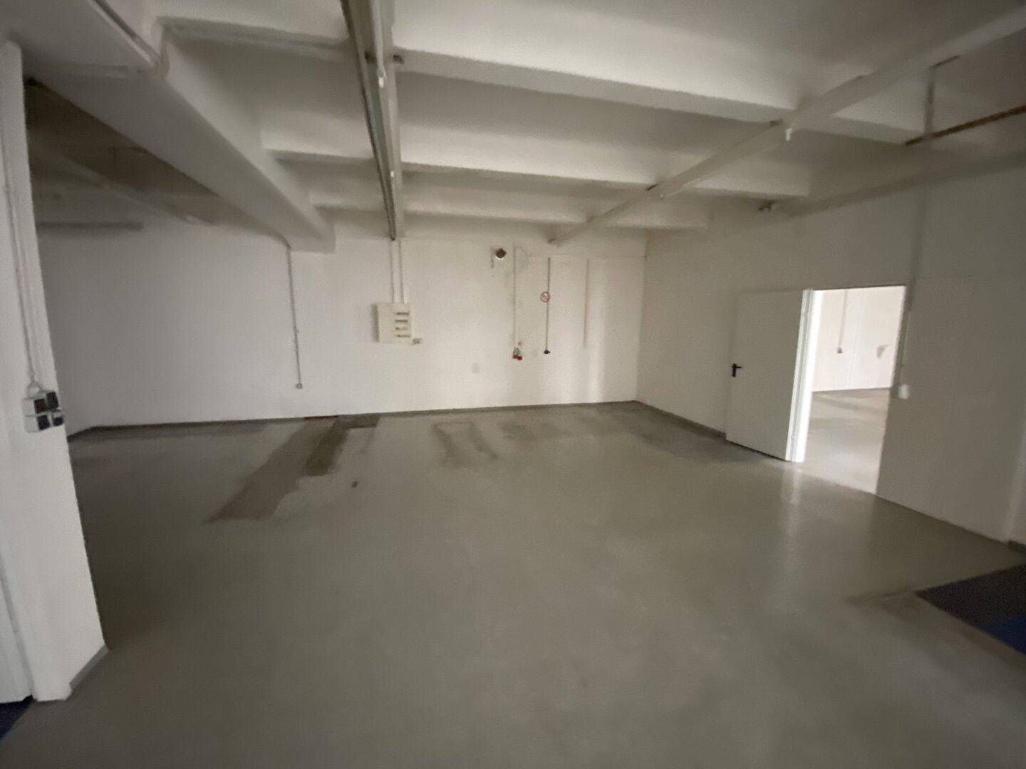Leerer Raum mit Betonboden und sichtbaren Installationen, geeignet als Lager oder Technikraum.