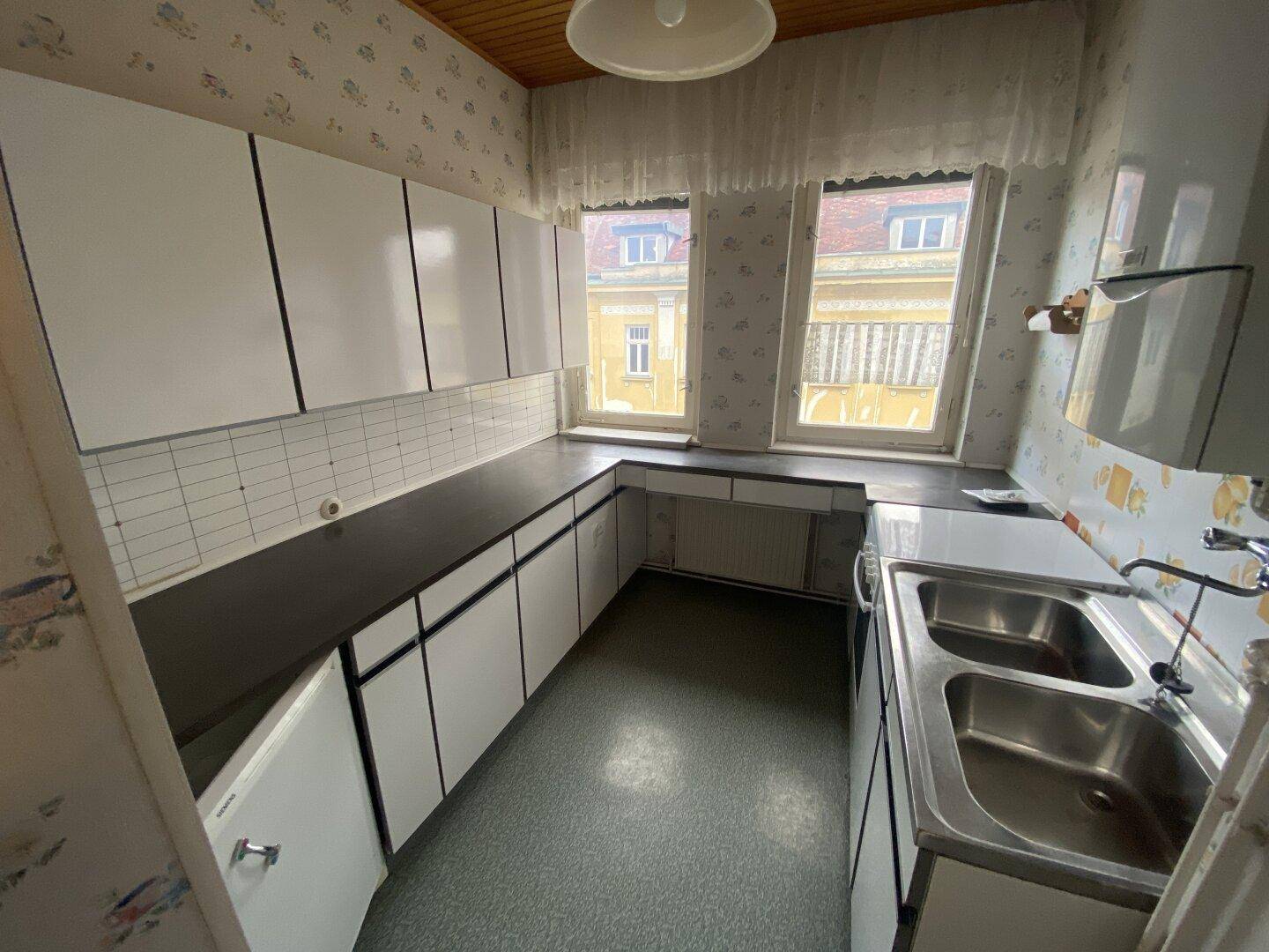 Geräumige Küche mit weißen Schränken, Doppelspüle und zwei Fenstern.