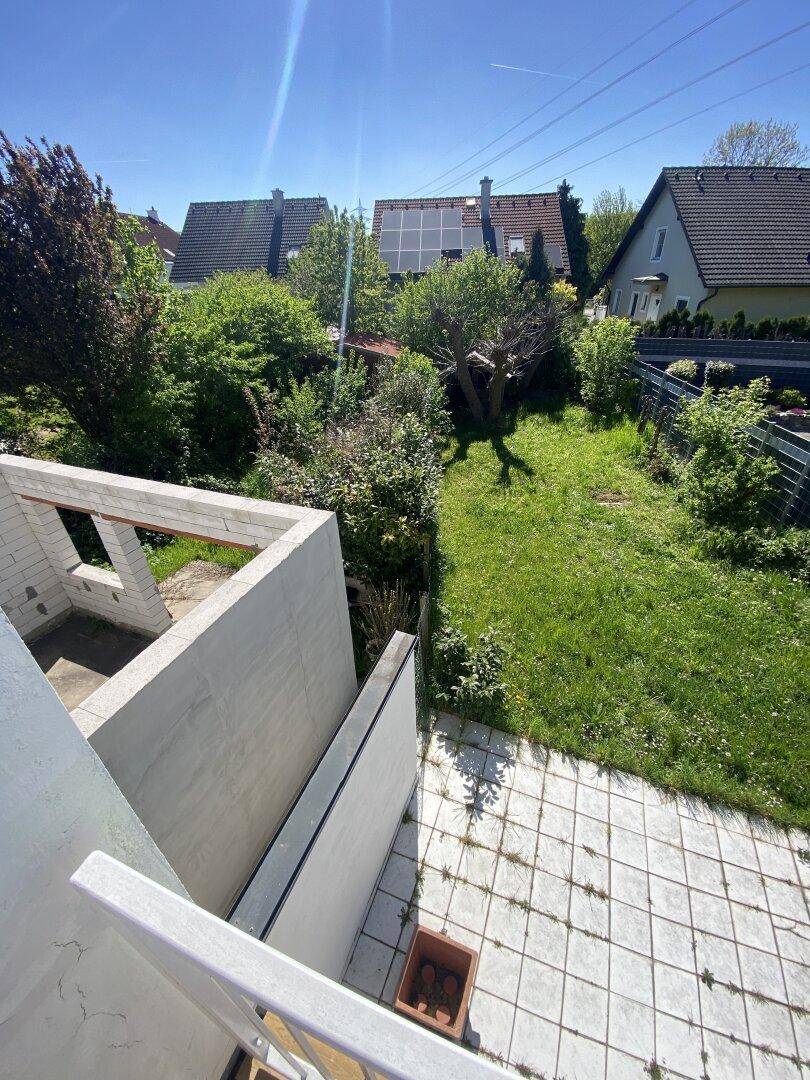 Weitläufiger Gartenbereich mit Bäumen und Blick auf benachbarte Häuser.