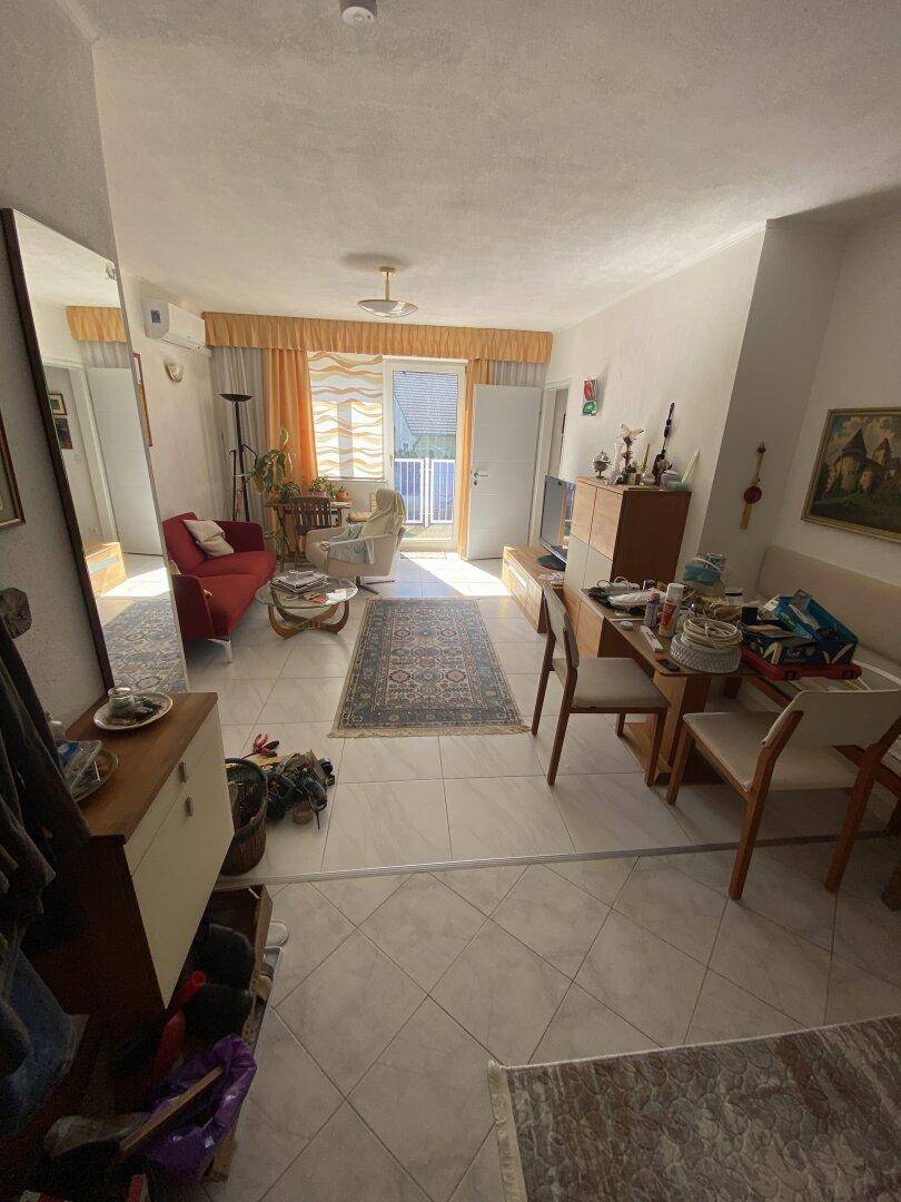 Geräumiger Wohn-Essbereich mit Fliesenboden und Zugang zum Balkon.