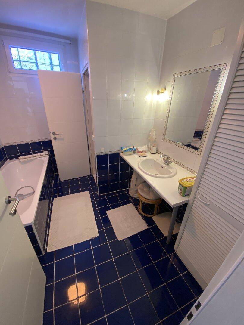 Badezimmer mit Badewanne, Waschbecken und blauen Fliesen.
