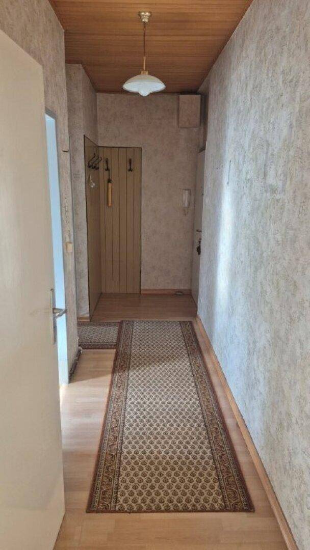 Langer Flur mit Parkettboden, Holzdecke und Garderobe im Eingangsbereich.