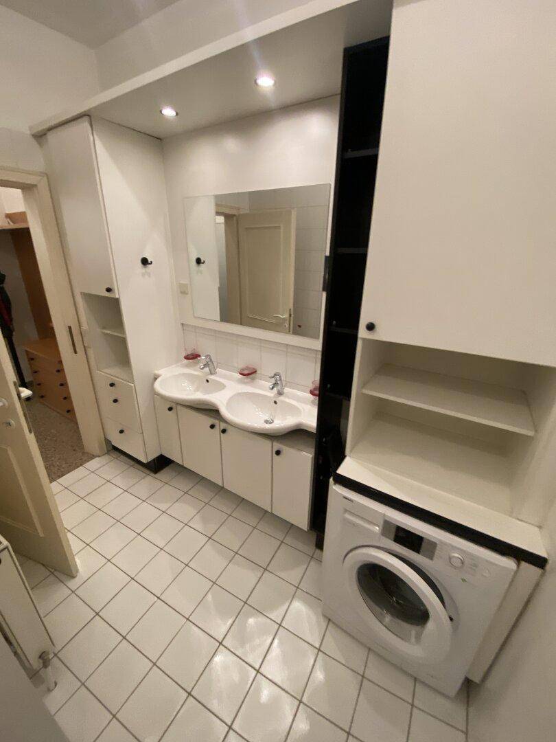 Geräumiges Badezimmer mit Doppelwaschbecken, viel Stauraum und integrierter Waschmaschine.