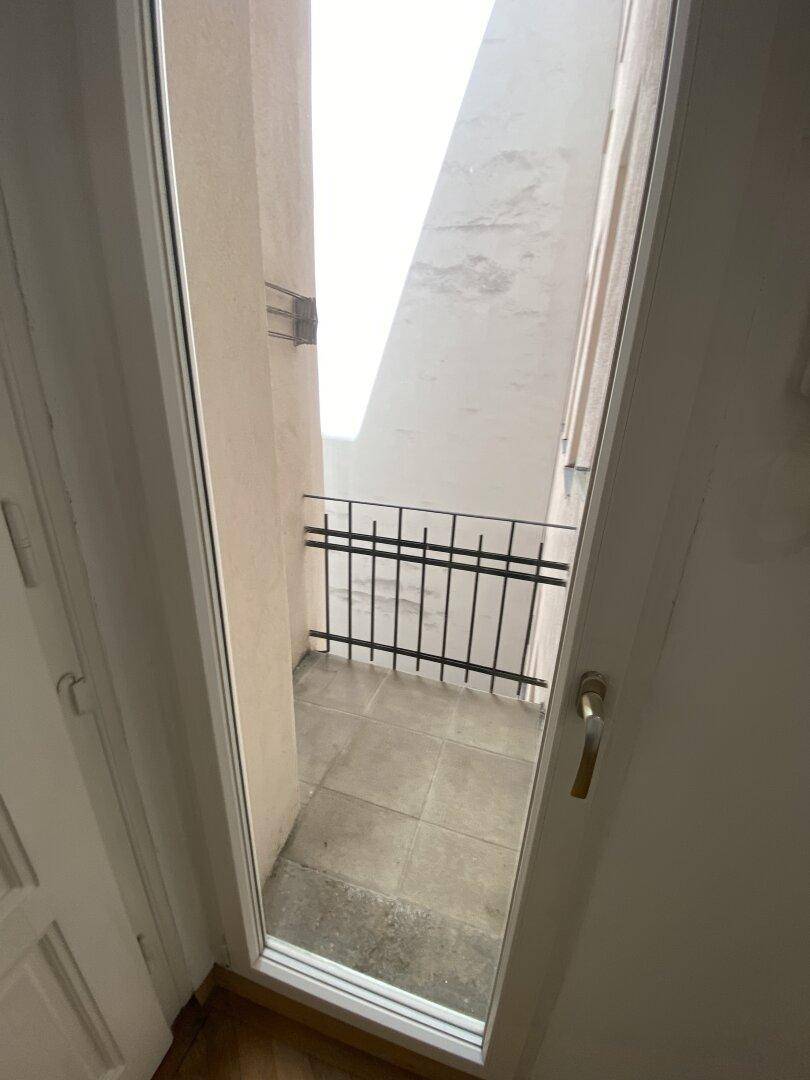 Kleiner, gefliester Balkon mit Metallgeländer und Blick auf den Innenhof.