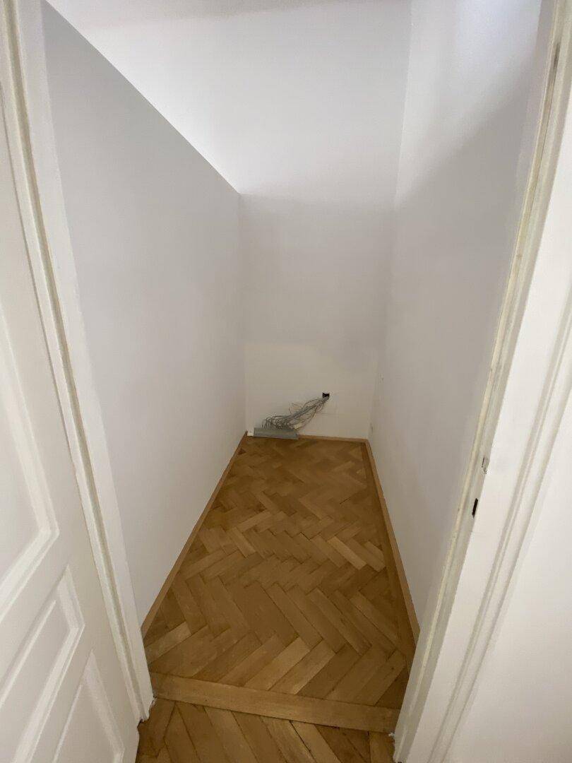 Kleiner Abstellraum mit Fischgrätparkett und weißen Wänden, ideal für zusätzlichen Stauraum.