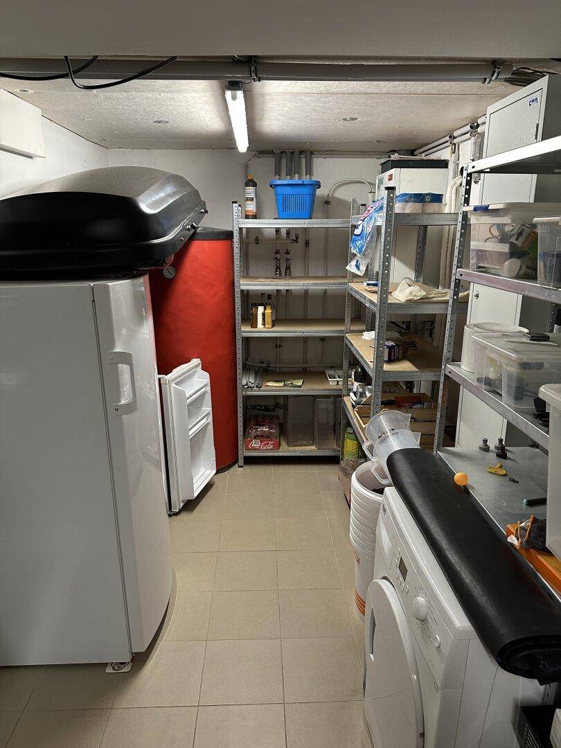 Praktischer Hauswirtschaftsraum im Keller mit Regalen, Kühlschrank und Waschmaschine für zusätzlichen Stauraum.