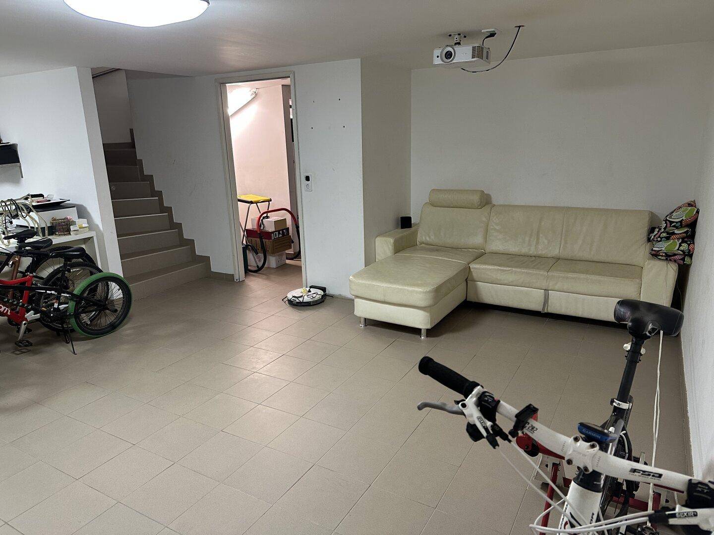 Heller Kellerraum mit beigem Sofa und Projektor, ideal als Freizeitbereich oder Medienzimmer.