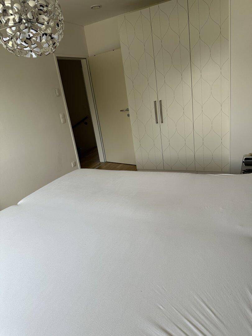 Schlafzimmeransicht mit großem Kleiderschrank und Zugang zu einem weiteren Raum, hell und funktional.