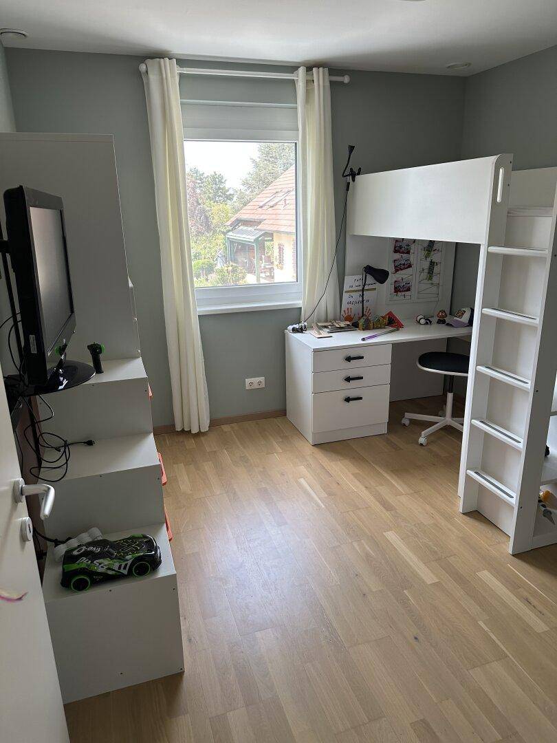 Kinderzimmer mit Hochbett, Schreibtisch und hellem Holzboden, bietet Platz zum Spielen und Lernen.