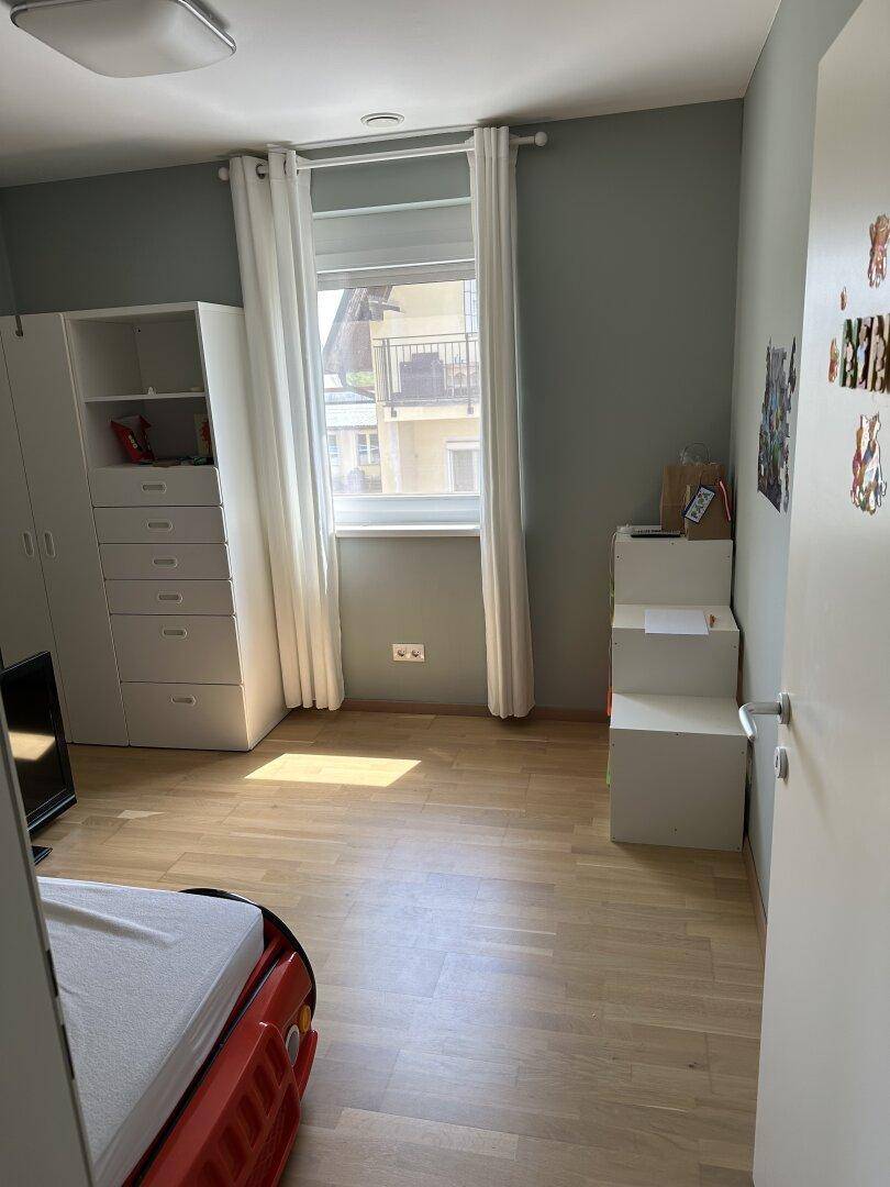 Helles Kinderzimmer mit Fenster und weißem Kleiderschrank, bietet eine freundliche Lernumgebung.