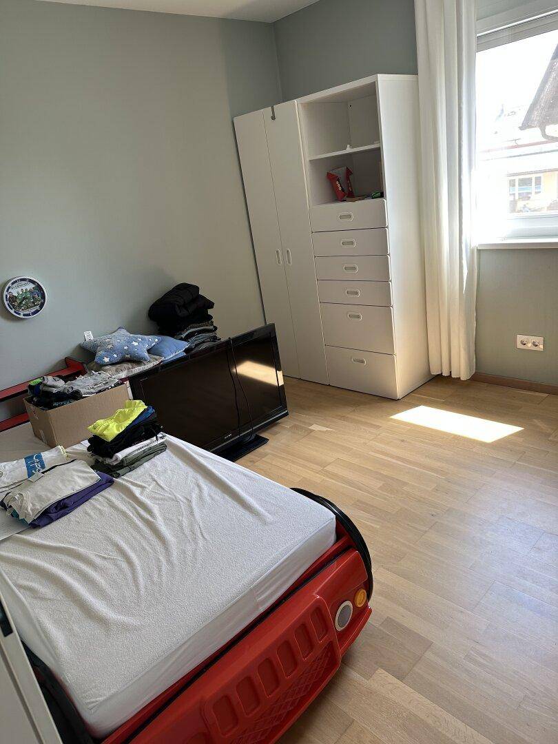 Kinderzimmer mit kreativem Autobett und weißem Kleiderschrank, bietet eine spielerische Atmosphäre.
