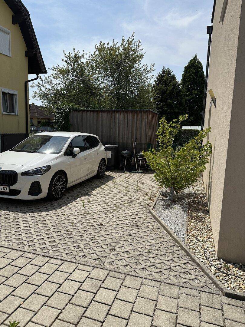 Gepflasterte Einfahrt mit ausreichend Platz für ein Fahrzeug, umgeben von Grünflächen.